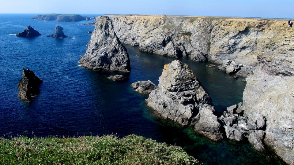 silhouettes d'un couple au loin sur une falaise au bord de l'océan